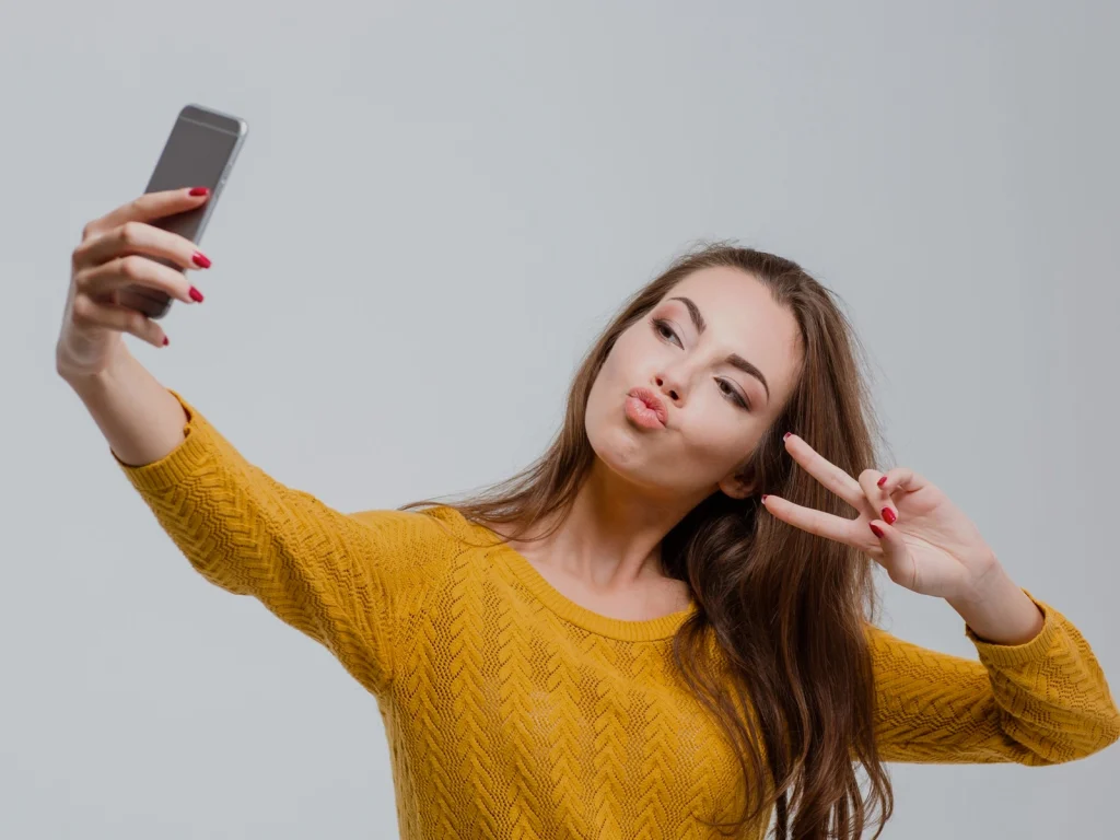 Selfie çeken genç kadın – sosyal medya etkisiyle estetik ameliyat tercihini temsil eden görsel
